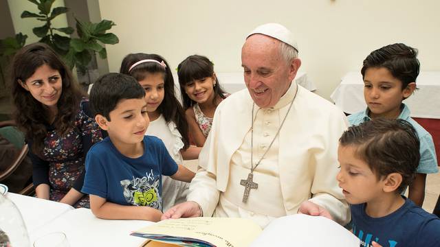 Pope Francis sits with some Siryans refugees at the Vatican 