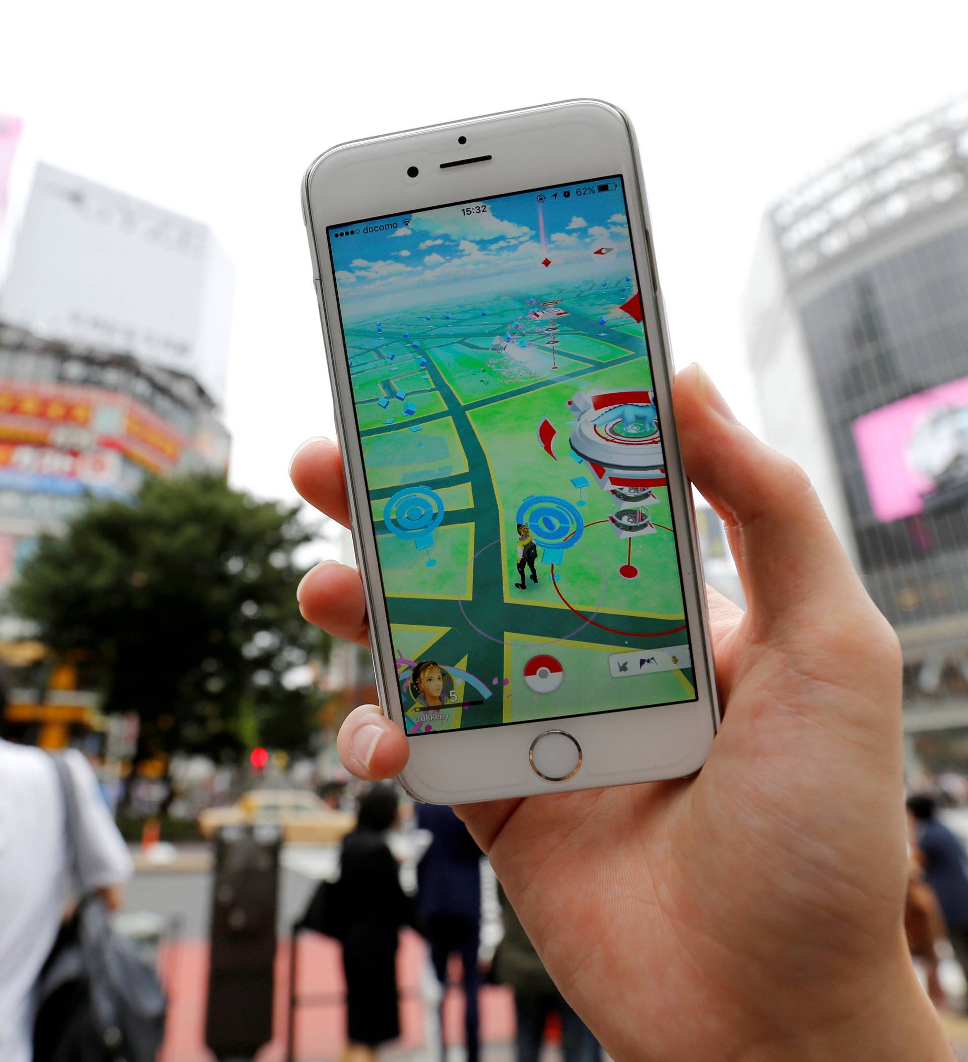 A man poses with his mobile phone displaying the augmented reality mobile game "Pokemon Go" by Nintendo in front of a busy crossing in Shibuya district in Tokyo