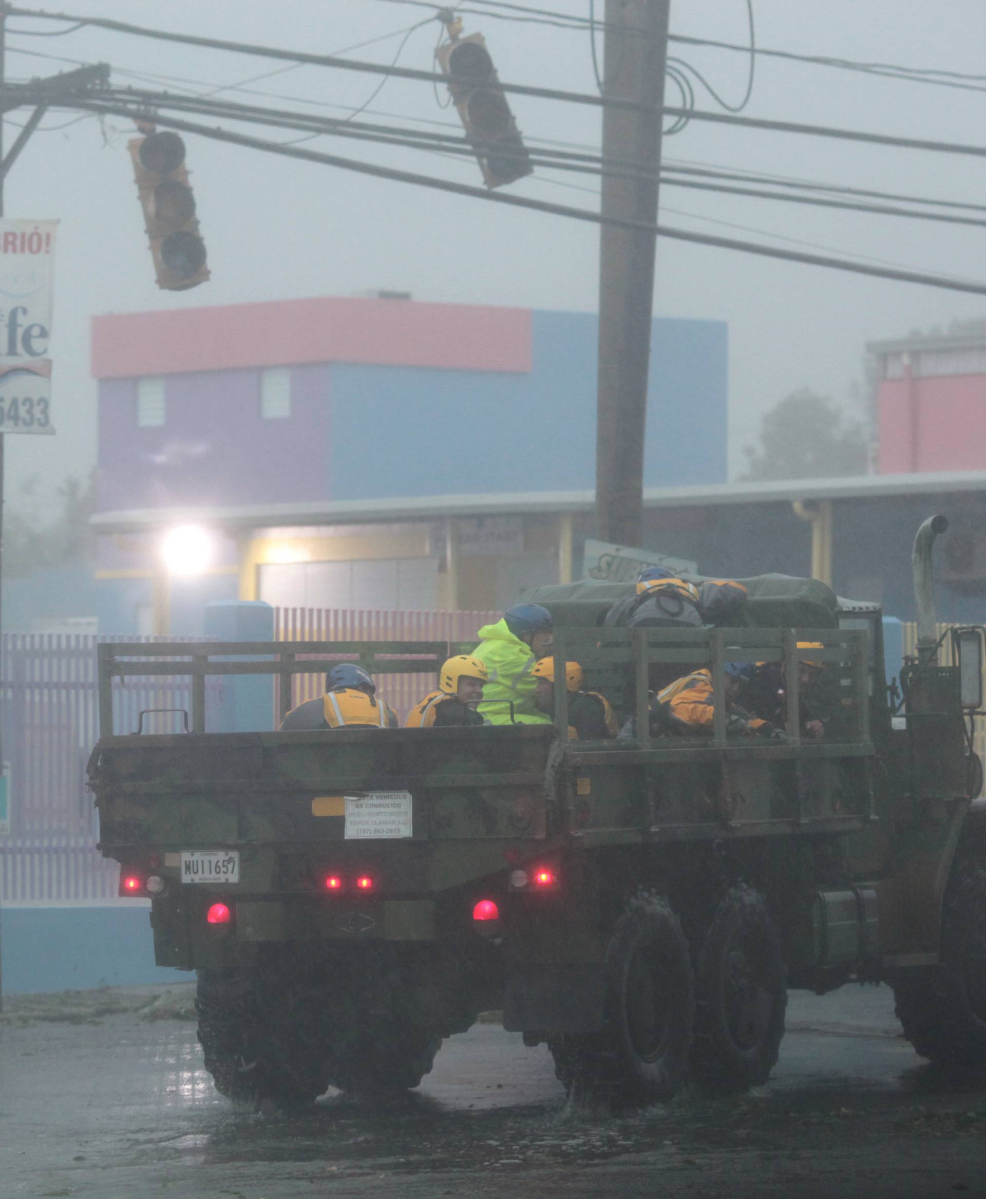 Members of the civil defense ride on a truck as Hurricane Irma howls past Puerto Rico after thrashing several smaller Caribbean islands, in Fajardo
