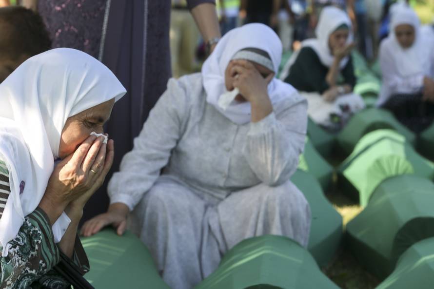 People mourn near coffins of their relatives, who are newly identified victims of the 1995 Srebrenica massacre, which are lined up for a joint burial in Potocari near Srebrenica