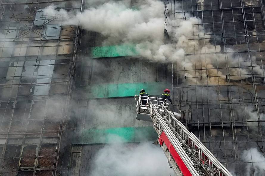 Firefighters work after a fire broke out at a karaoke lounge in Hanoi