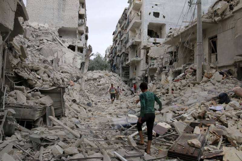 People inspect a damaged site after airstrikes on the rebel held Tariq al-Bab neighbourhood of Aleppo