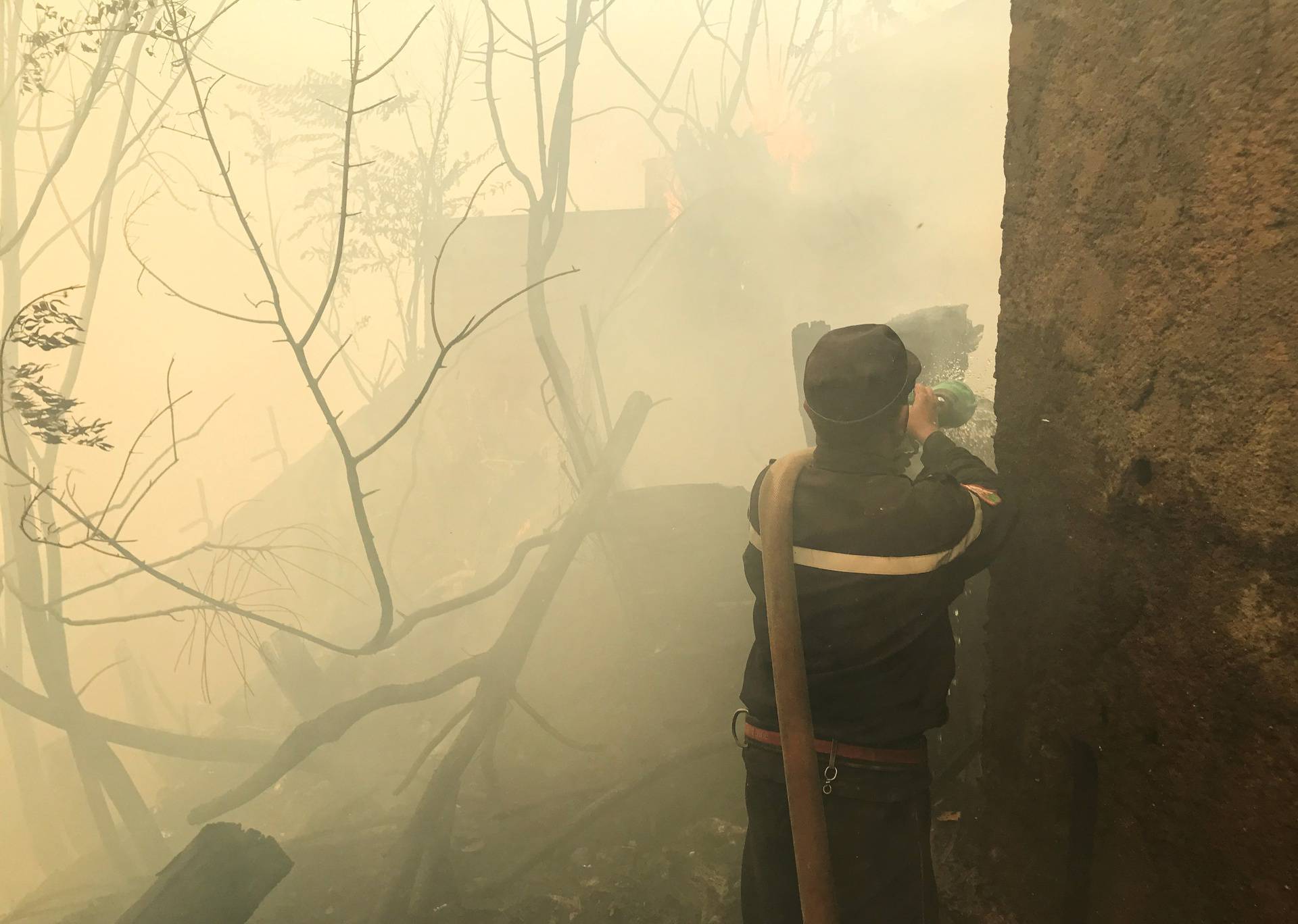 A firefighter attempt to put out a fire near a hospital in Ain al-Hammam village