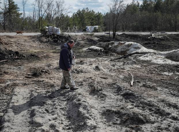 A dosimetrist measures the level of radiation around trenches dug by the Russian military in an area with high levels of radiation called the Red Forest near the Chernobyl Nuclear Power Plant, in Chernobyl