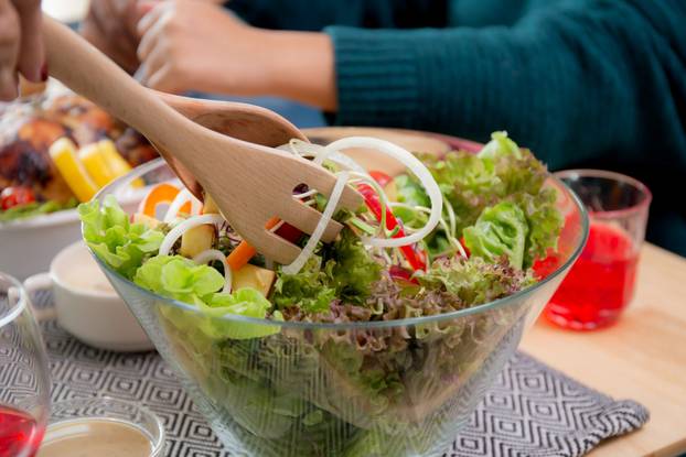 Closeup hands of woman mixing salad vegetable on bowl with spoon