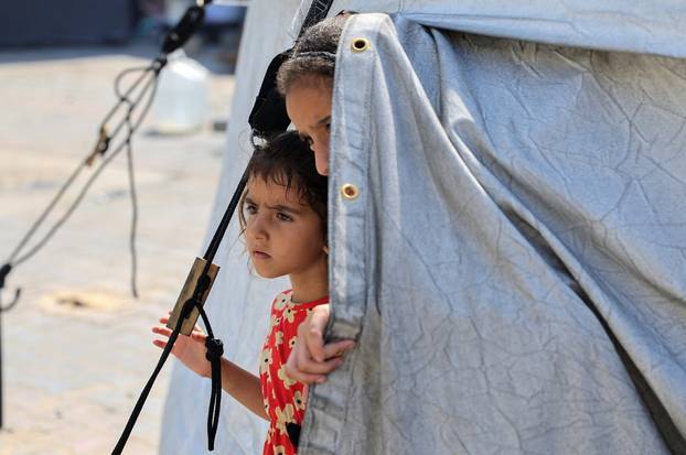 Displaced Palestinian children look out of a tent where they shelter, in Khan Younis, in the southern Gaza Strip
