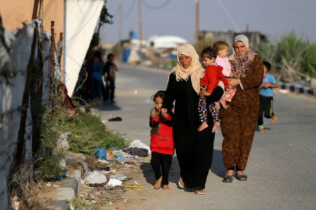 Palestinian women carry children as they walk on a street in the southern Gaza Strip