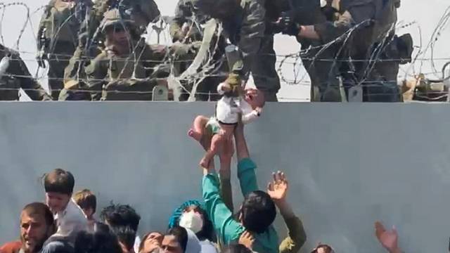 FILE PHOTO: A baby is handed over to the American army over the perimeter wall of the airport in Kabul