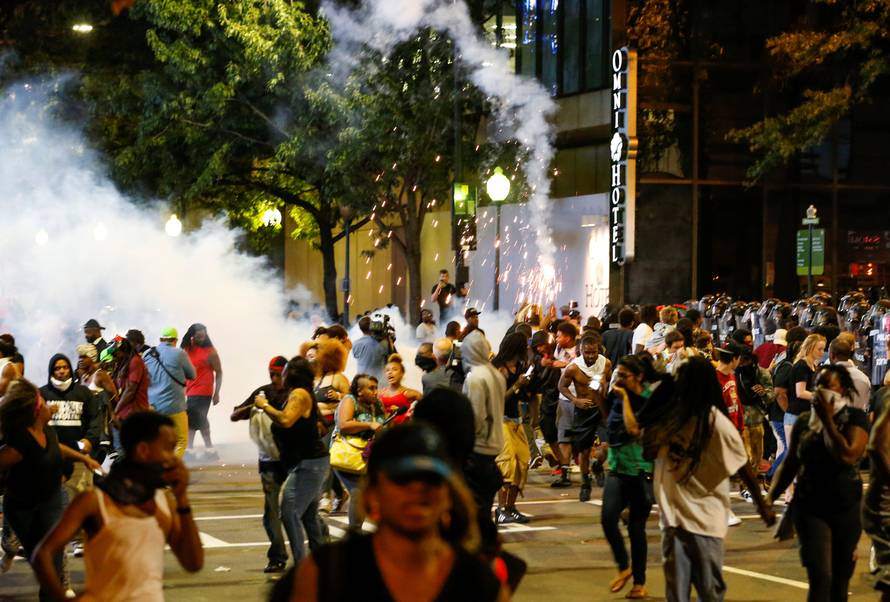 People run from flash-bang grenades in uptown Charlotte, NC during a protest of the police shooting of Keith Scott, in Charlotte