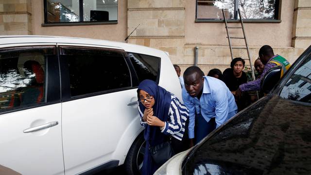 People are evacuated by a member of security forces at the scene where explosions and gunshots were heard at the Dusit hotel compound, in Nairobi