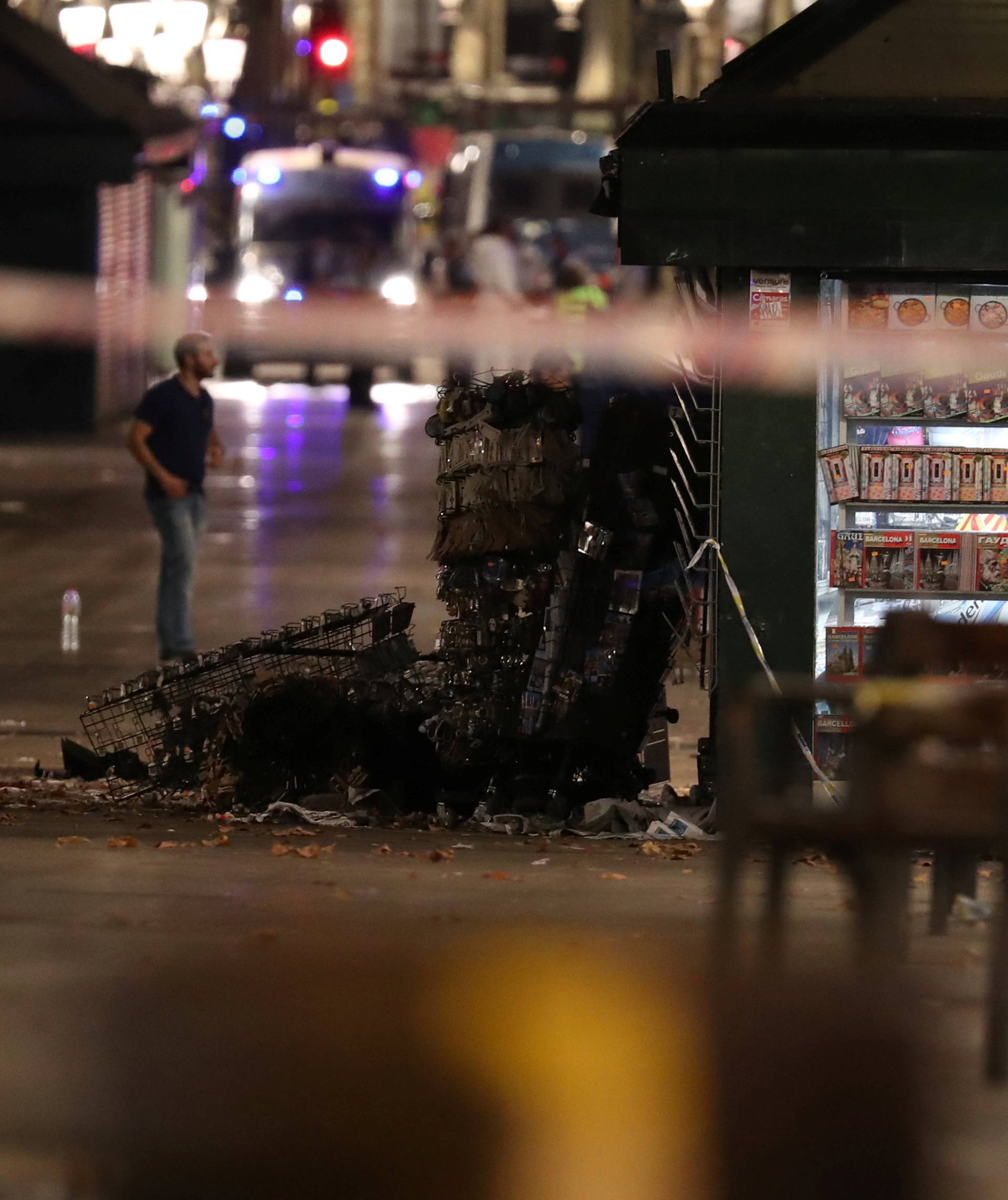 A officer walks past a fallen post cards display near the area where a van crashed into pedestrians at Las Ramblas in Barcelona