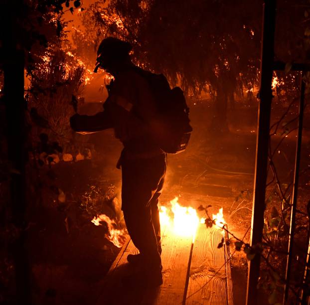 A firefighter battles a wind-driven wildfire called the Saddle Ridge fire in the early morning hours Friday in Porter Ranch