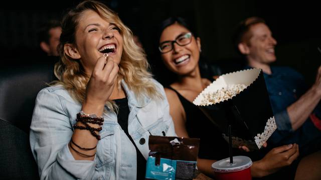 Young,Woman,With,Friends,Watching,Movie,In,Cinema,And,Laughing.