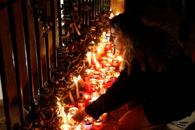 A woman places a candle on the Love monument during a silent candlelight vigil to protest against the assassination of investigative journalist Daphne Caruana Galizia in a car bomb attack, in St Julian