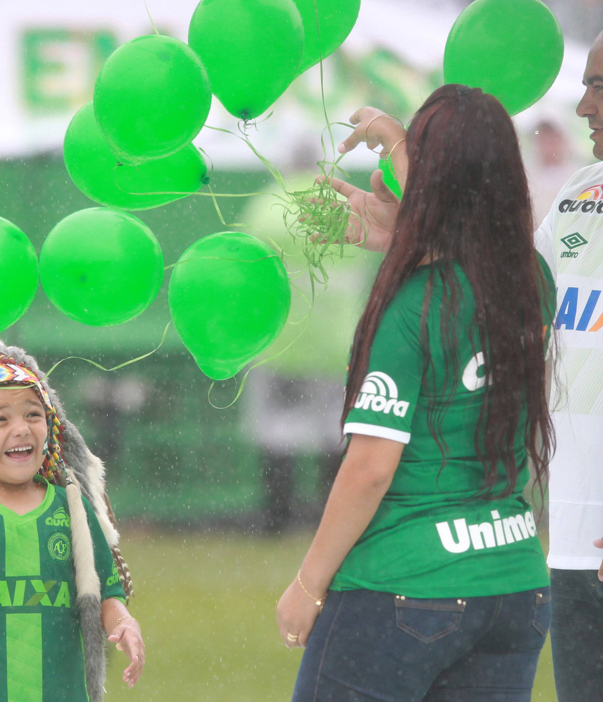 Carlinhos (L) represent the mascot Indian Conda of Chapecoense with his parents while paying tribute to the victims of the plane crash in Colombia at Arena Conda stadium in Chapeco
