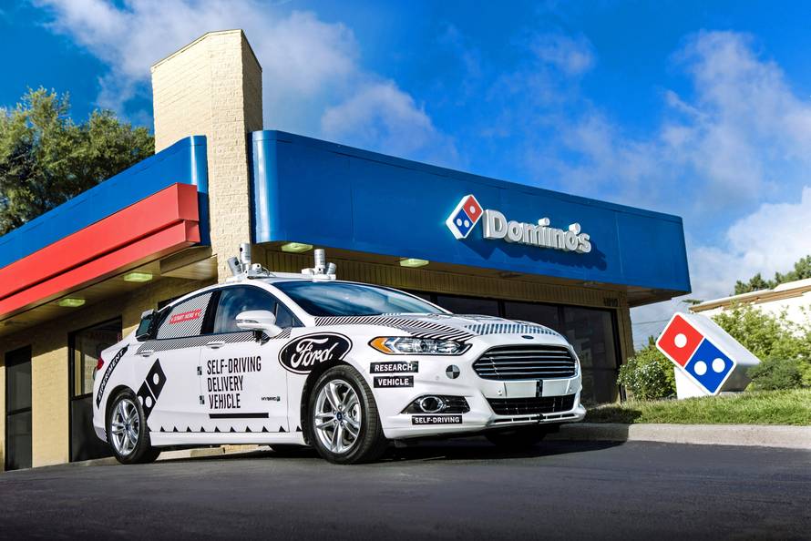A Ford self-driving delivery vehicle is pictured in front of a Domino's pizza restaurant in this handout photo