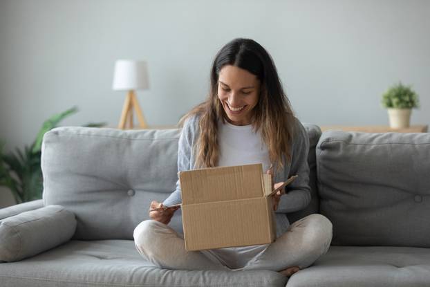 Overjoyed,Woman,Seated,On,Sofa,Hold,On,Lap,Small,Cardboard