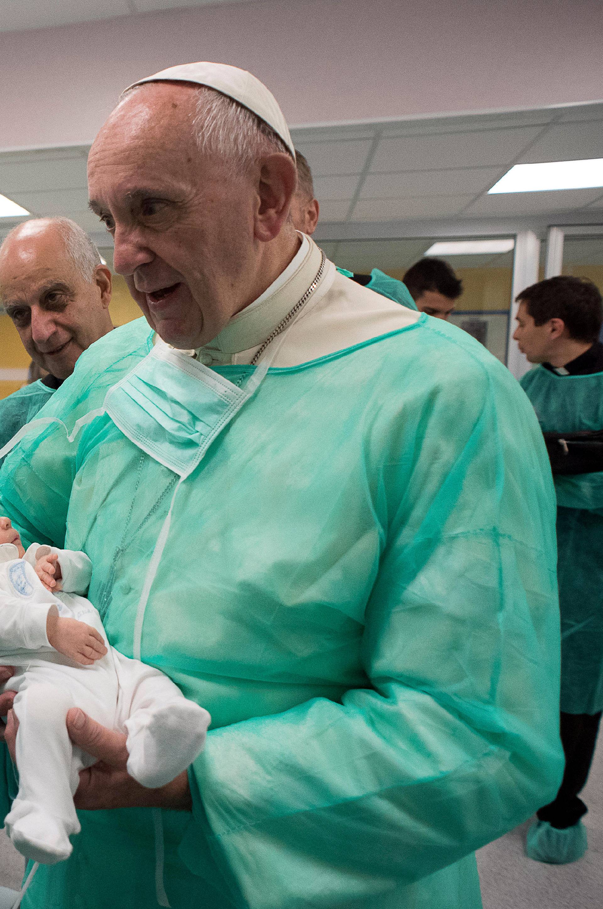 Pope Francis holds newly-born baby as he visits the San Giovanni hospital in Rome
