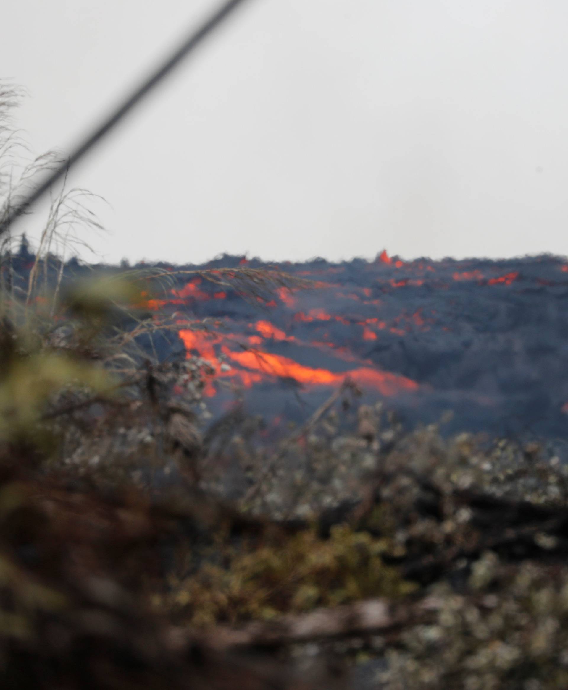 Molten rock from the Kilauea volcano pours down the side of the lava flow on Pohoiki Road near Pahoa, Hawaii