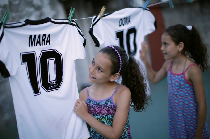 Mara and Dona, twin daughters of Walter Gaston Rotundo,a devoted Diego Maradona fan who named his daughters after the soccer star, look at t-shirts with their names, in Buenos Aires