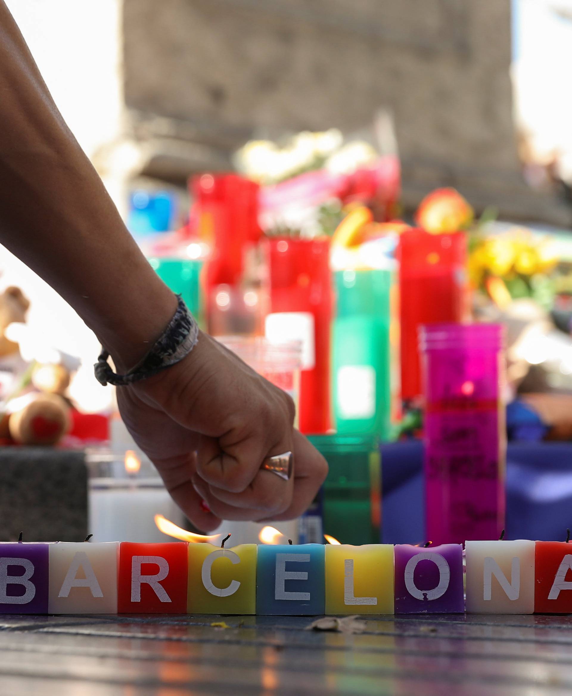 A man lights a candle in an impromptu memorial a day after a van crashed into pedestrians at Las Ramblas in Barcelona