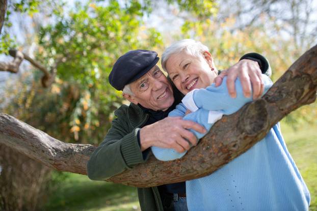 Portrait of aged couple standing near tree
