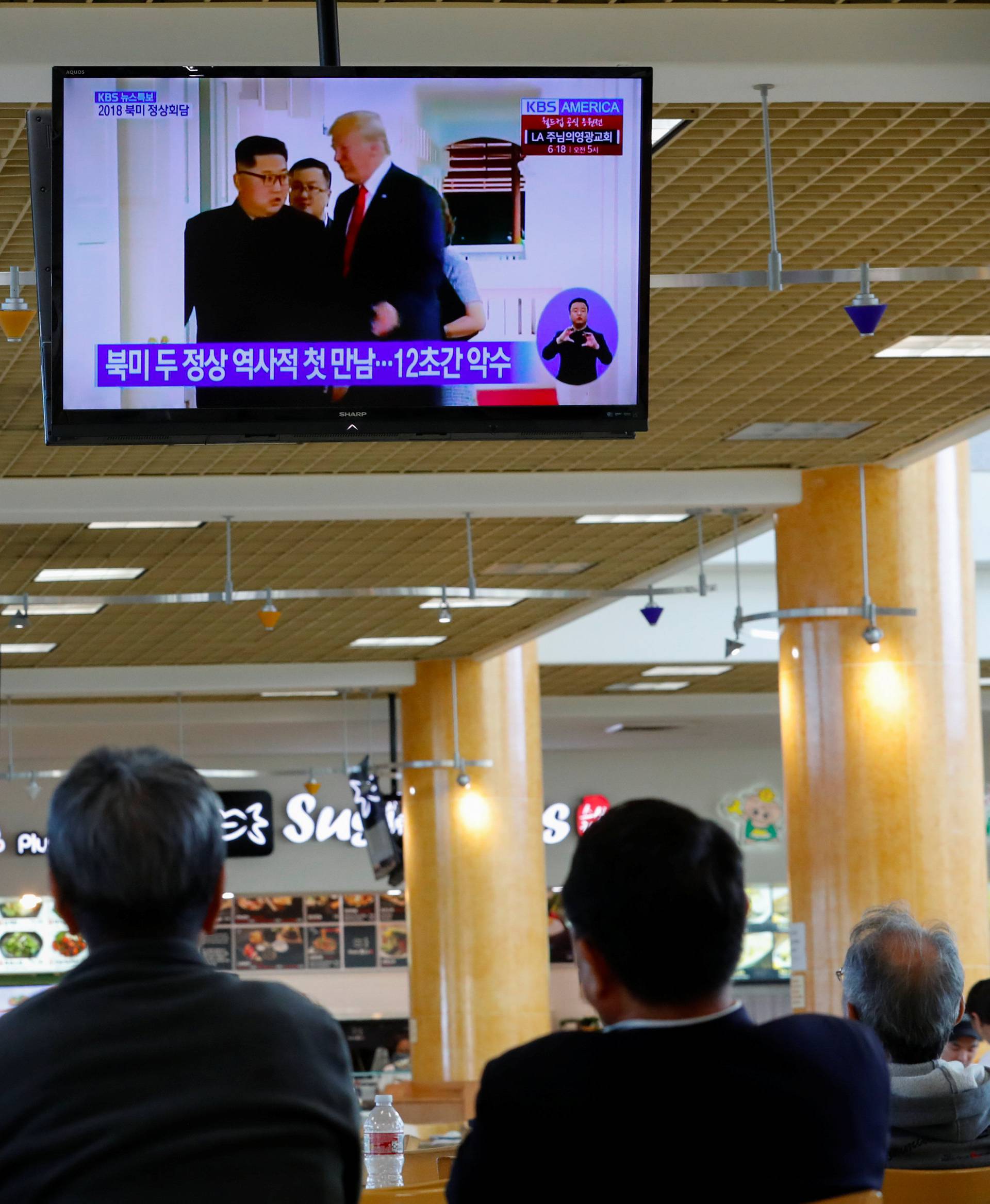 People watch from a shopping mall food court  in the Los Angeles neighborhood of Koreatown as Singapore hosts a summit between U.S. President Donald Trump and North Korean leader Kim Jong Un in Los Angeles