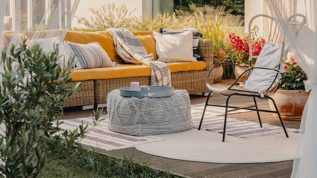 Real photo of an armchair, pouf as a table and wicker couch on a terrace