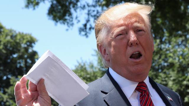 U.S. President Trump holds copy of regional asylum plan as he departs for travel to Iowa from the White House in Washington