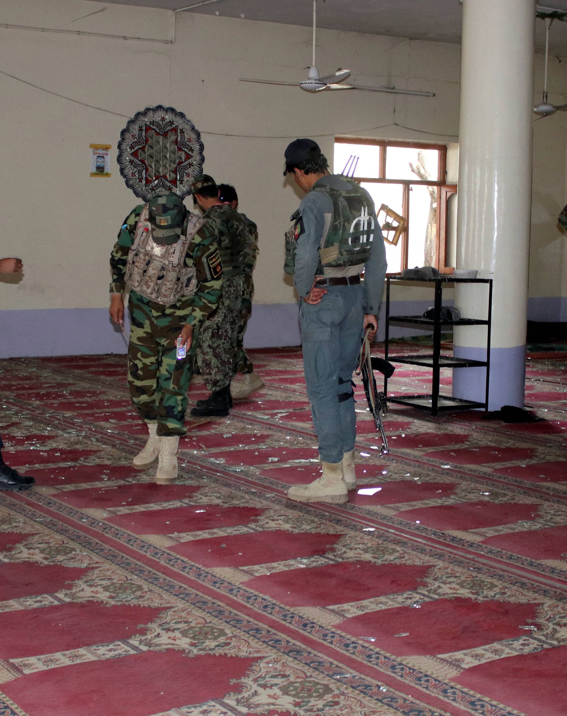 Afghan policemen inspect a mosque after a blast in Khost province