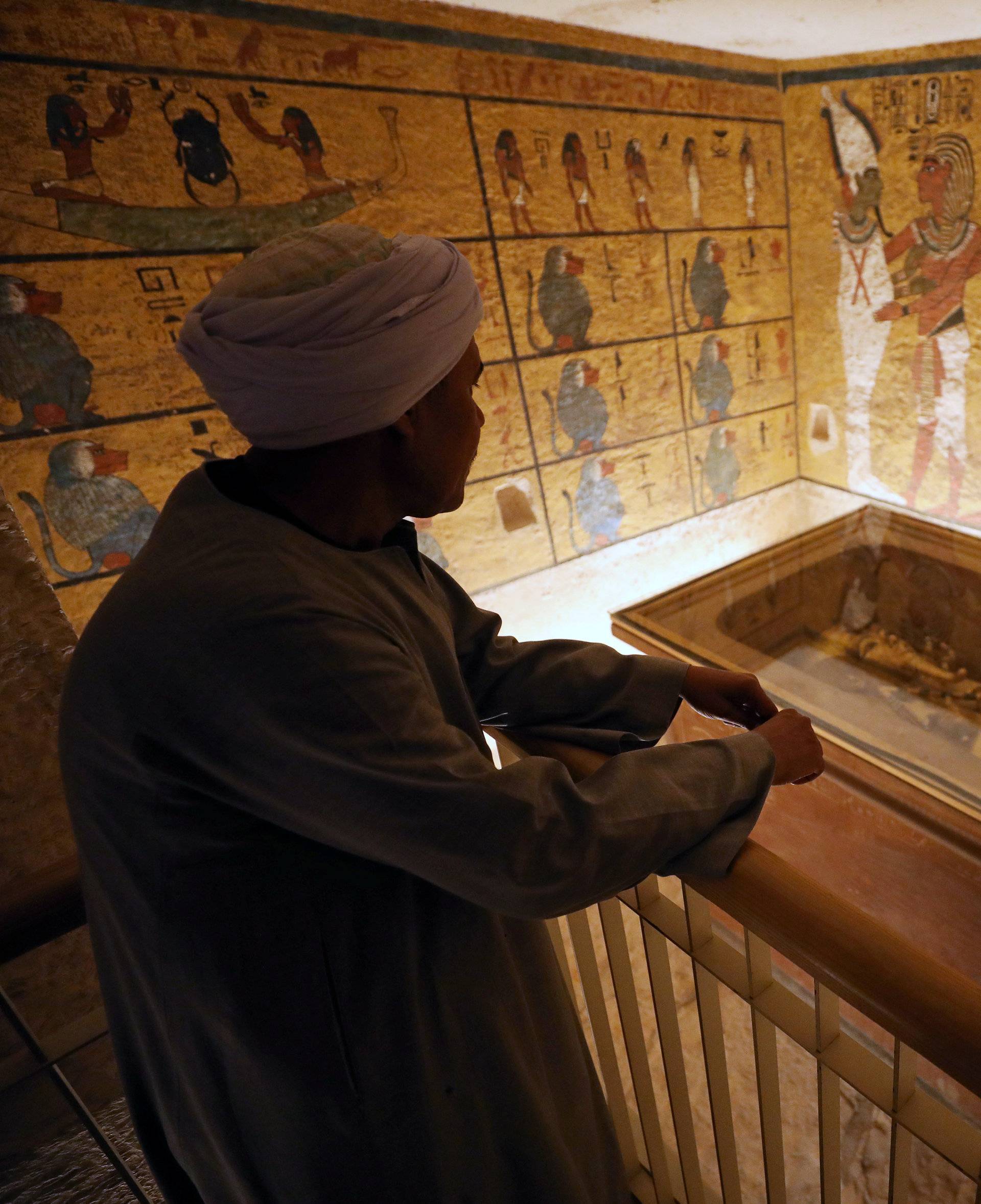 A guard looks at ancient Egyptian drawings and the sarcophagus in the newly renovated tomb wall of boy pharaoh King Tutankhamun in the Valley of the Kings in Luxor