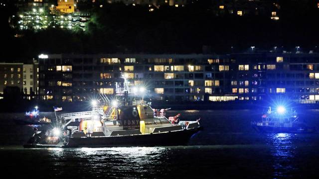 An FDNY fire department boat searches the Hudson River for the wreckage of a vintage P-47 Thunderbolt airplane that crashed in the river in New York City