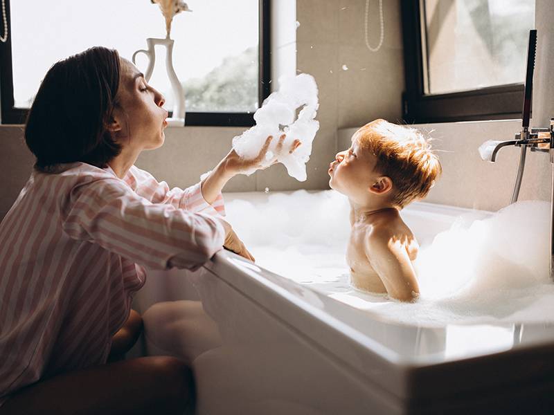 Mother washing little son in bathroom