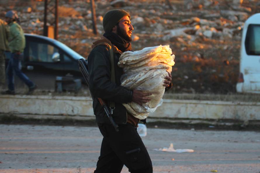 A rebel fighter carries bread for evacuees from rebel-held east Aleppo, upon their arrival to the town of al-Rashideen