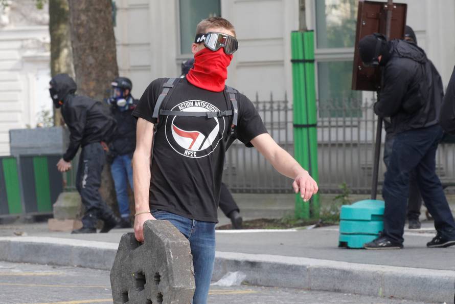 A demonstrator carries a piece of barrier, as he wears a t-shirt reading: "antifascist action", during clashes with French CRS riot police at the May Day labour union rally in Paris
