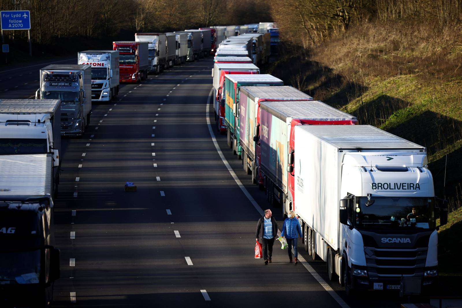 People walk by a line of parked lorries on the outskirts of Dover