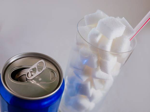 conceptual still life image of glass with straw full sugar cubes and soda refresh drink  in unhealthy nutrition sugar addiction and refreshments massive calories content