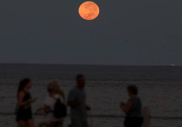 A full moon sets during a total lunar eclipse, in Cape Town