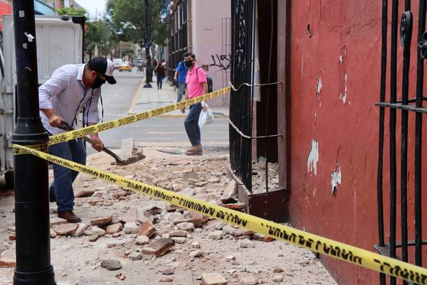 A man removes debris from a building damaged during a quake, in Oaxaca