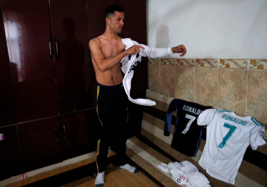 Biwar Abdullah, 25, an Iraqi Kurdish local footballer, who looks like the football player Cristiano Ronaldo, wears his shirt at his home in the district of Soran, northeast of Erbil
