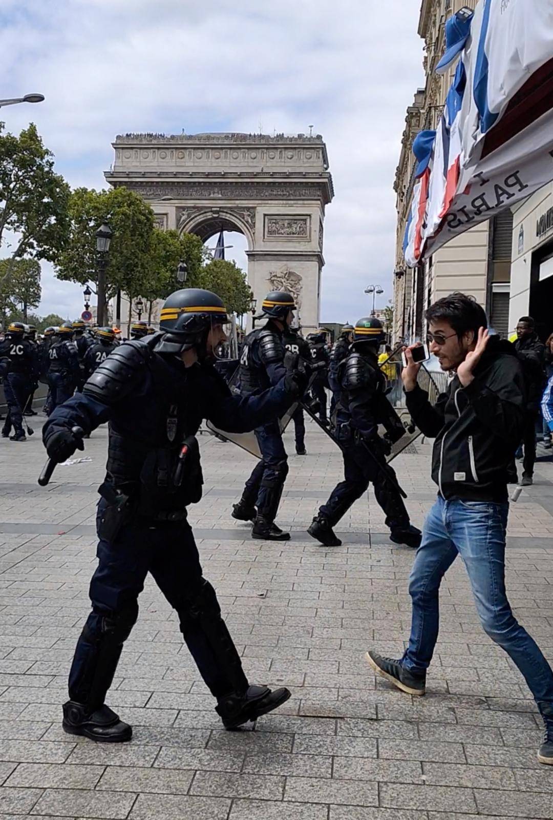 A police officer gestures to a man during clashes with protesters on Champs Elysees in Paris
