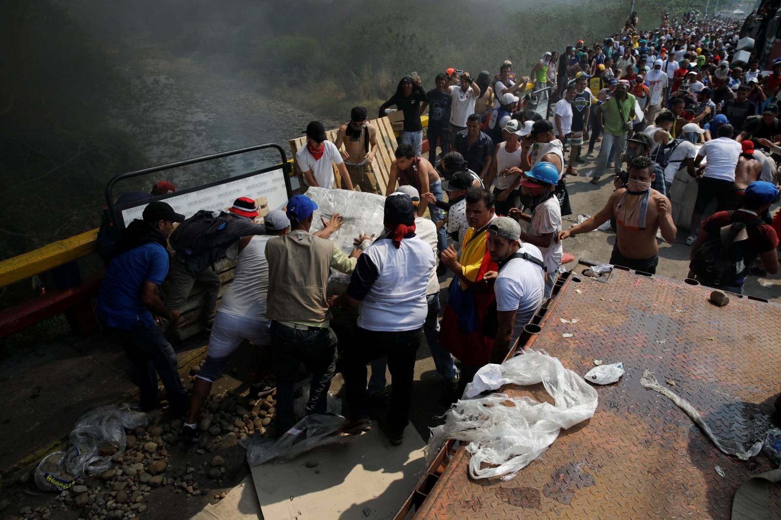 Opposition supporters unload humanitarian aid from a truck that was sent on fire in Cucuta