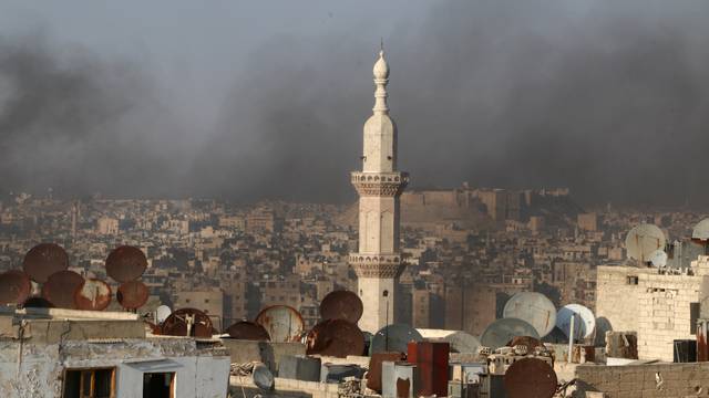 Smoke from burning tyres rises near a minaret of a mosque, which activists said are used to create smoke cover from warplanes, in Aleppo