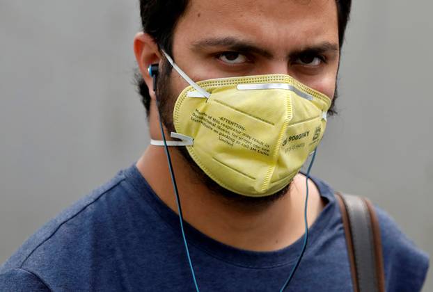 A man wearing a mask walks outside a metro station on a smoggy morning in New Delhi