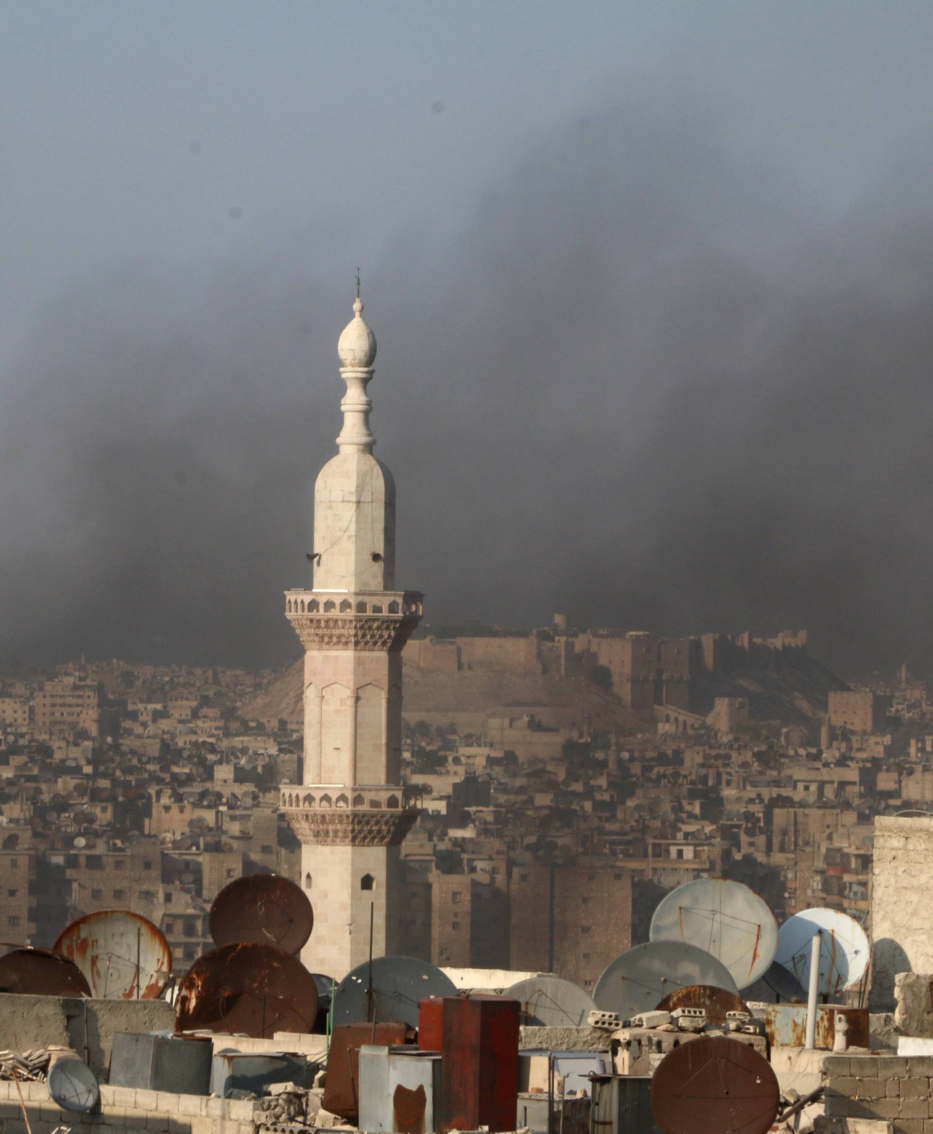 Smoke from burning tyres rises near a minaret of a mosque, which activists said are used to create smoke cover from warplanes, in Aleppo