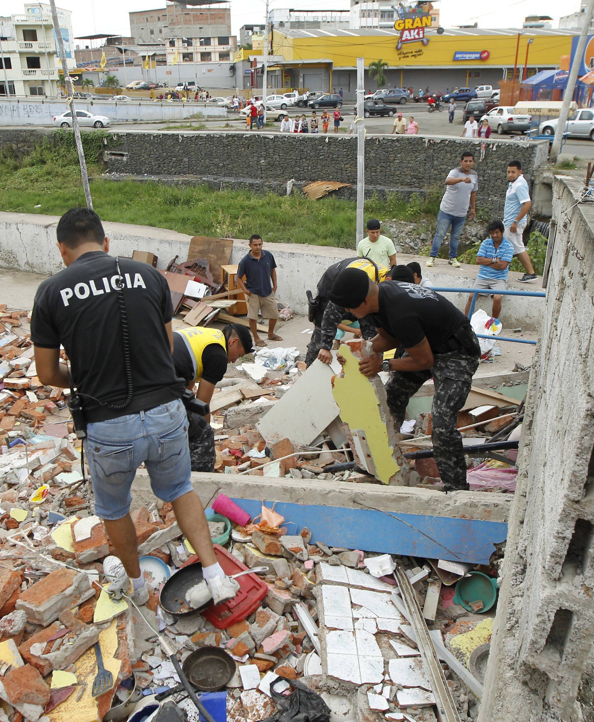 Police officers search through debris after an earthquake struck off Ecuador's Pacific coast, at Tarqui neighborhood in Manta