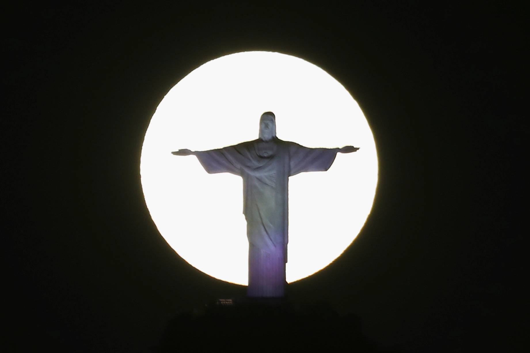 The super moon shines behind the Christ the Redeemer statue in Rio de Janeiro
