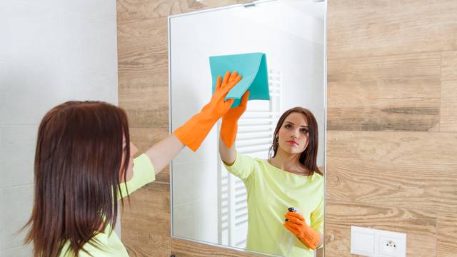 The young woman cleans a bathroom.
