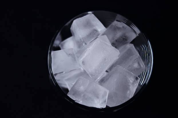 A glass full of ice cubes view from above close up on a black background.