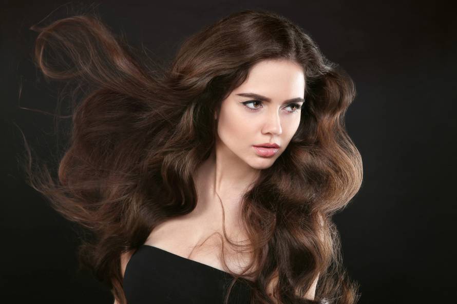 Beauty hair. Brunette girl with long shiny wavy hair. Beautiful 